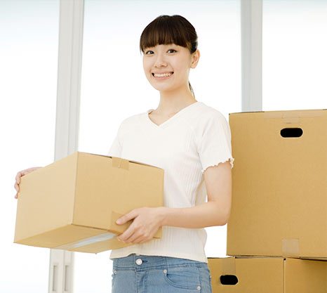 不用品を梱包したダンボールを持つ女性の写真